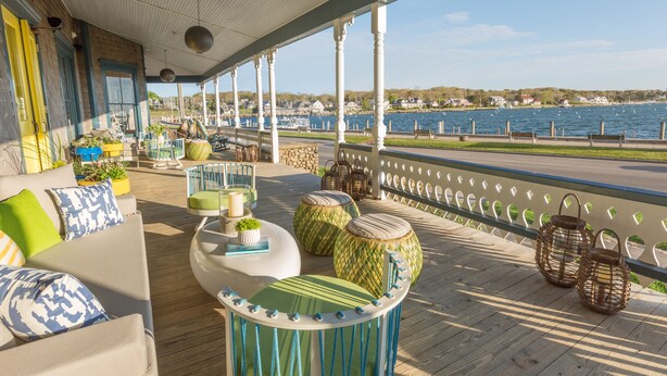 A covered outdoor area with a wooden deck, seating, and a view of the water. - Summercamp (Oak Bluffs)