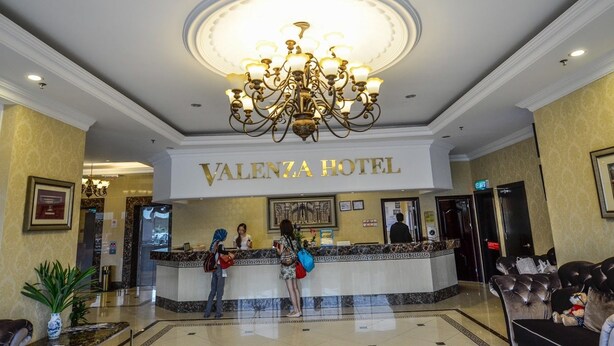 A reception area with a chandelier, a sign reading "Valenza Hotel," and a marble counter. - Valenza Hotel & Cafe (Kuala Lumpur)