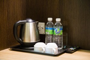 Una bandeja con una tetera, dos botellas de agua y dos tazas blancas sobre una superficie de madera.