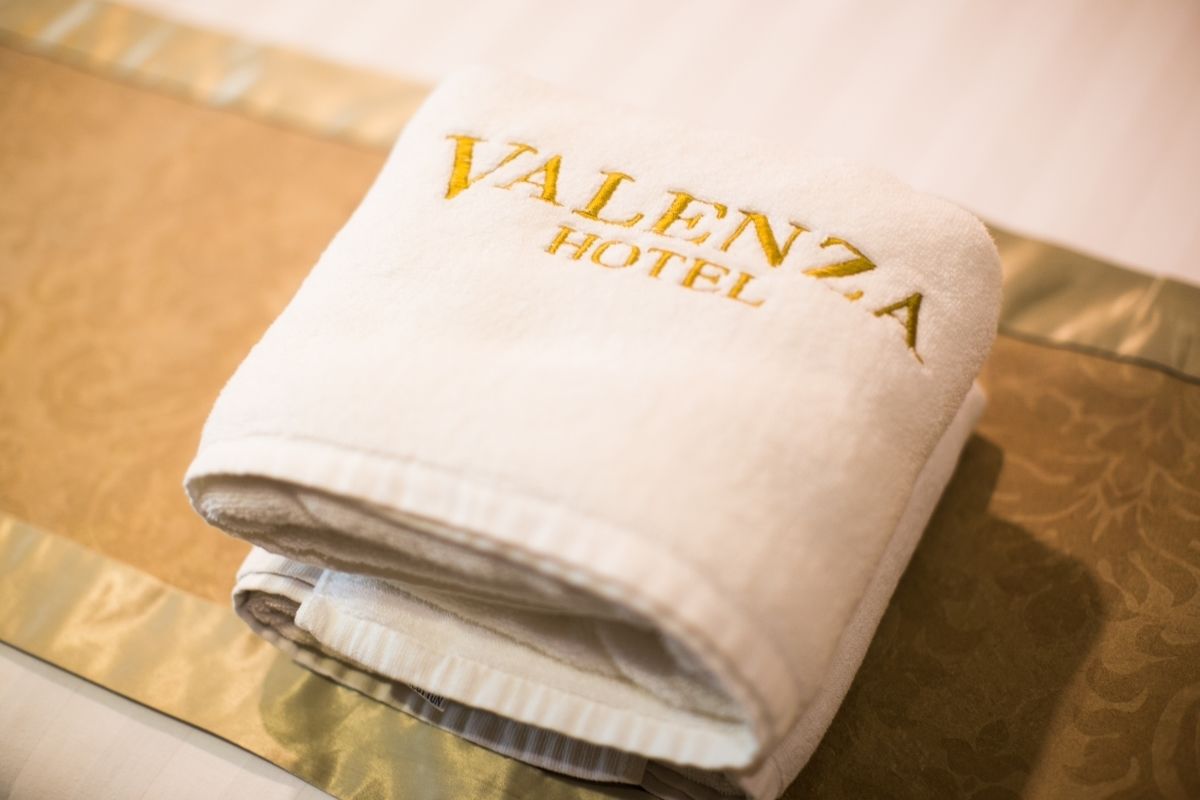 A folded towel with "Valencia Hotel" embroidered in gold.