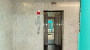 En elevator med væg i marmor, sikkerhedsskilt og kontrolpanel.