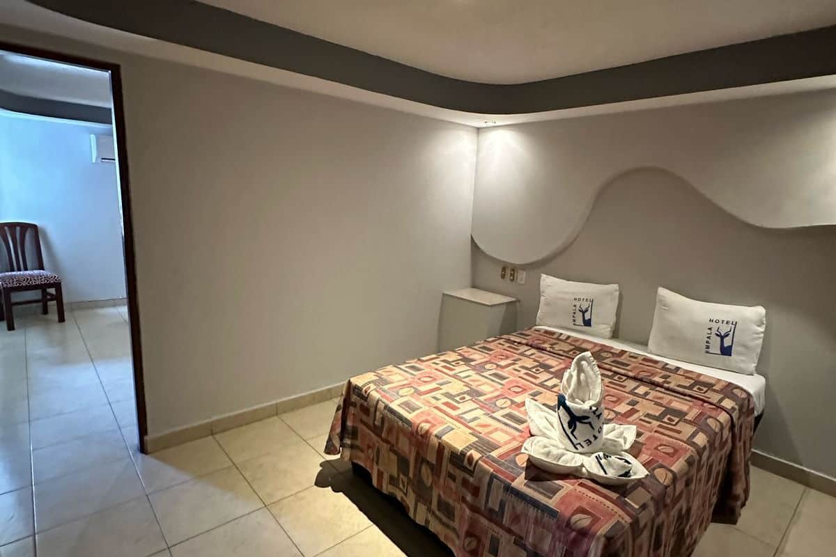 Une chambre d’hôtel avec un grand lit, une table de chevet et une chaise dans un coin.