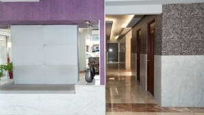 En moderne lobby med en skrivebord af marmor, mønstrede vægge og en gang, der fører til værelser.