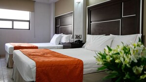 Une chambre d’hôtel avec deux lits simples, une table de chevet, un téléphone et une fenêtre.