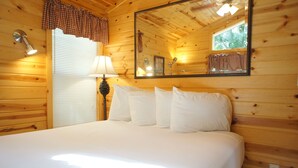 Een houten kamer met een groot bed, een spiegel, een lamp en een raam met zonwering.