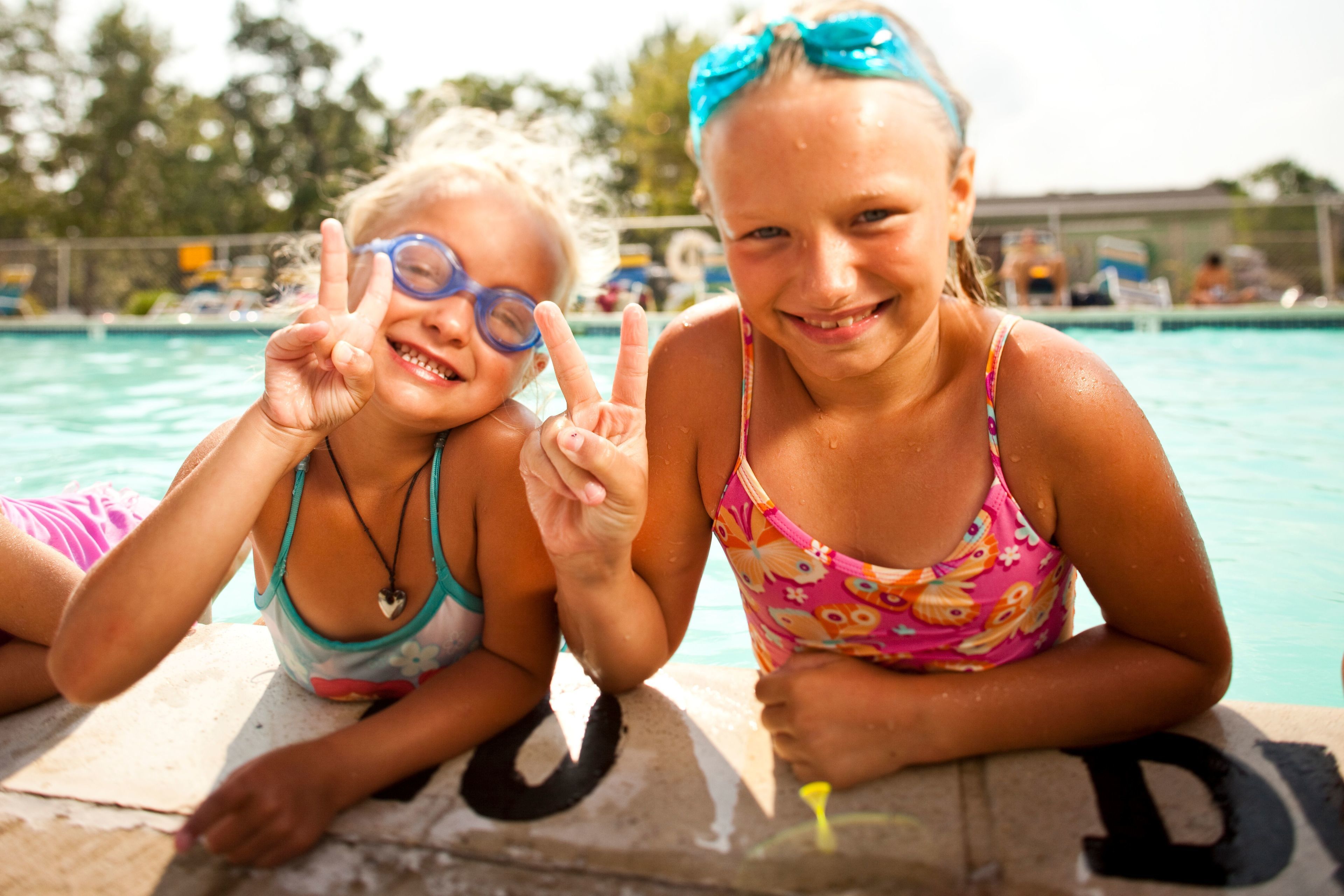 Two children sitting by a poolside with a letter 'D' on the ground.