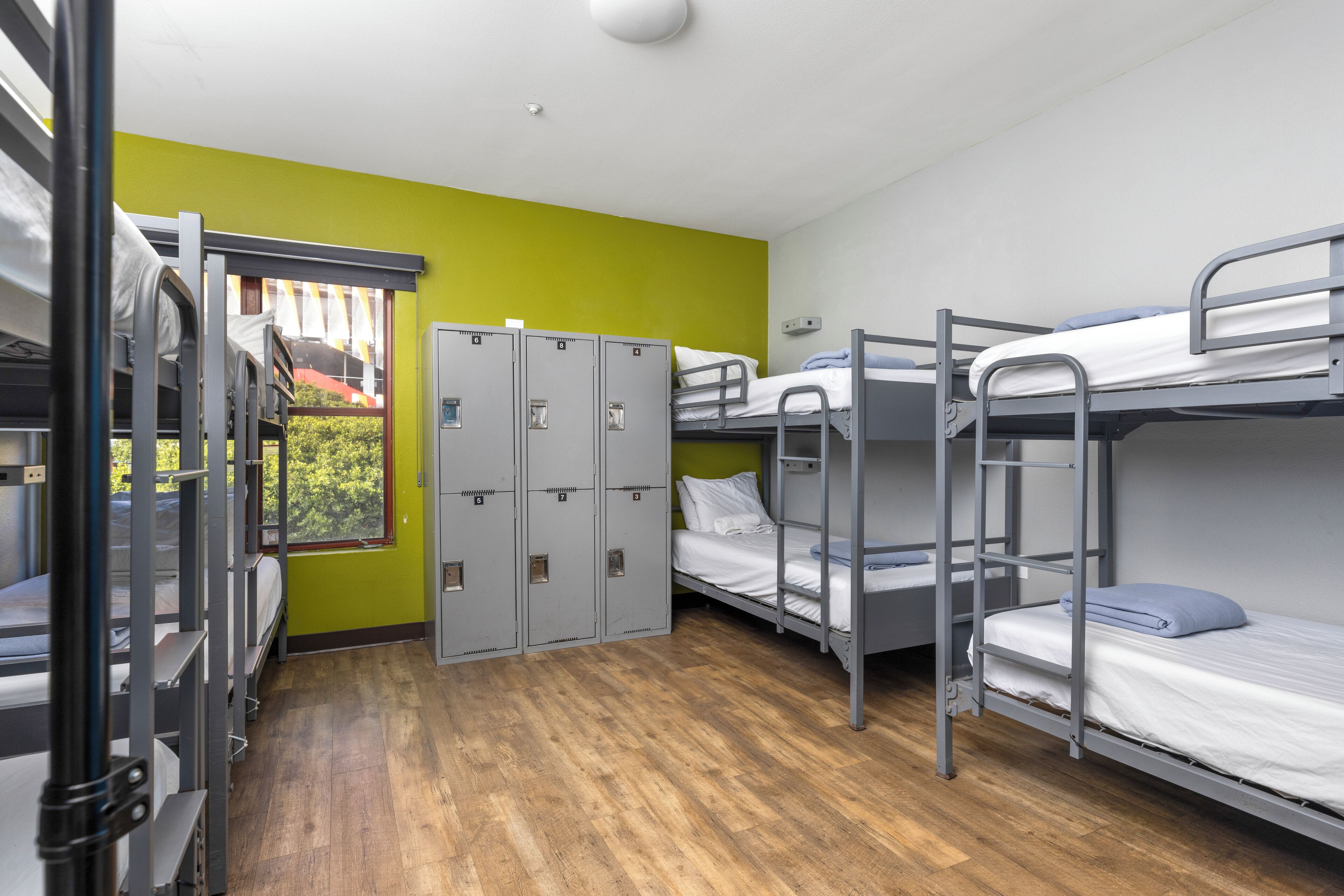 Un dormitorio con literas, una ventana y varios taquones.