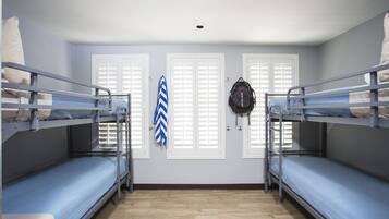 A room with bunk beds, a door with shutters, and a ceiling light.