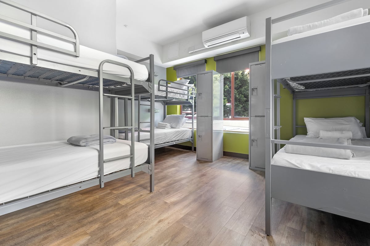 A dormitory room with bunk beds, a wardrobe, and a window with a view.