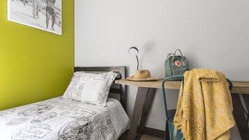 A room with a bed, a desk, a chair, a backpack, and a wall with a picture.