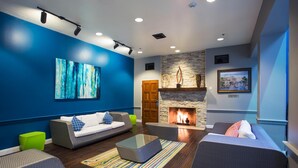 Una sala de estar moderna con chimenea, paredes azules y muebles contemporáneos.