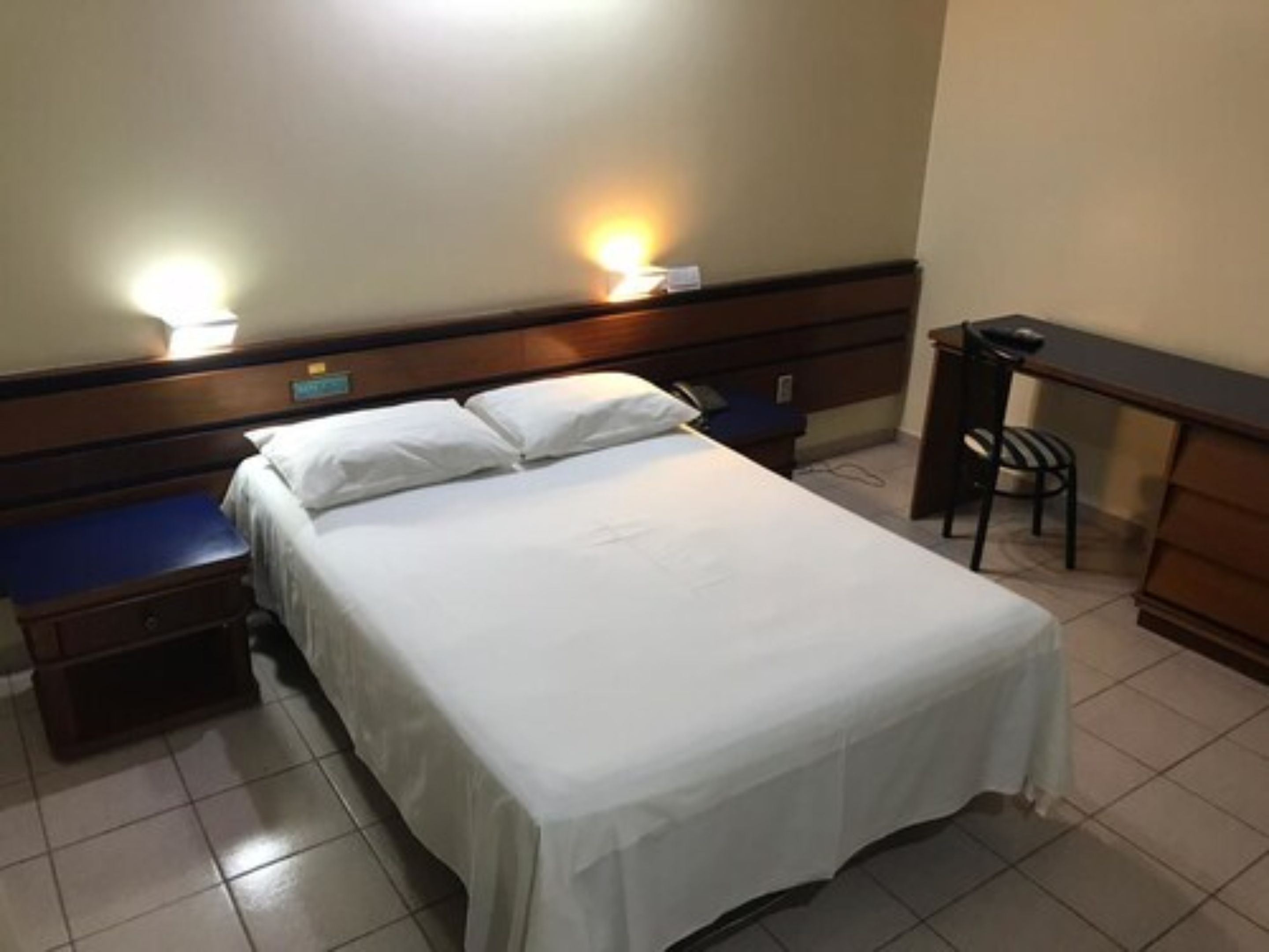 Ein Hotelzimmer mit Bett, Nachttischen, Schreibtisch und Stuhl.
