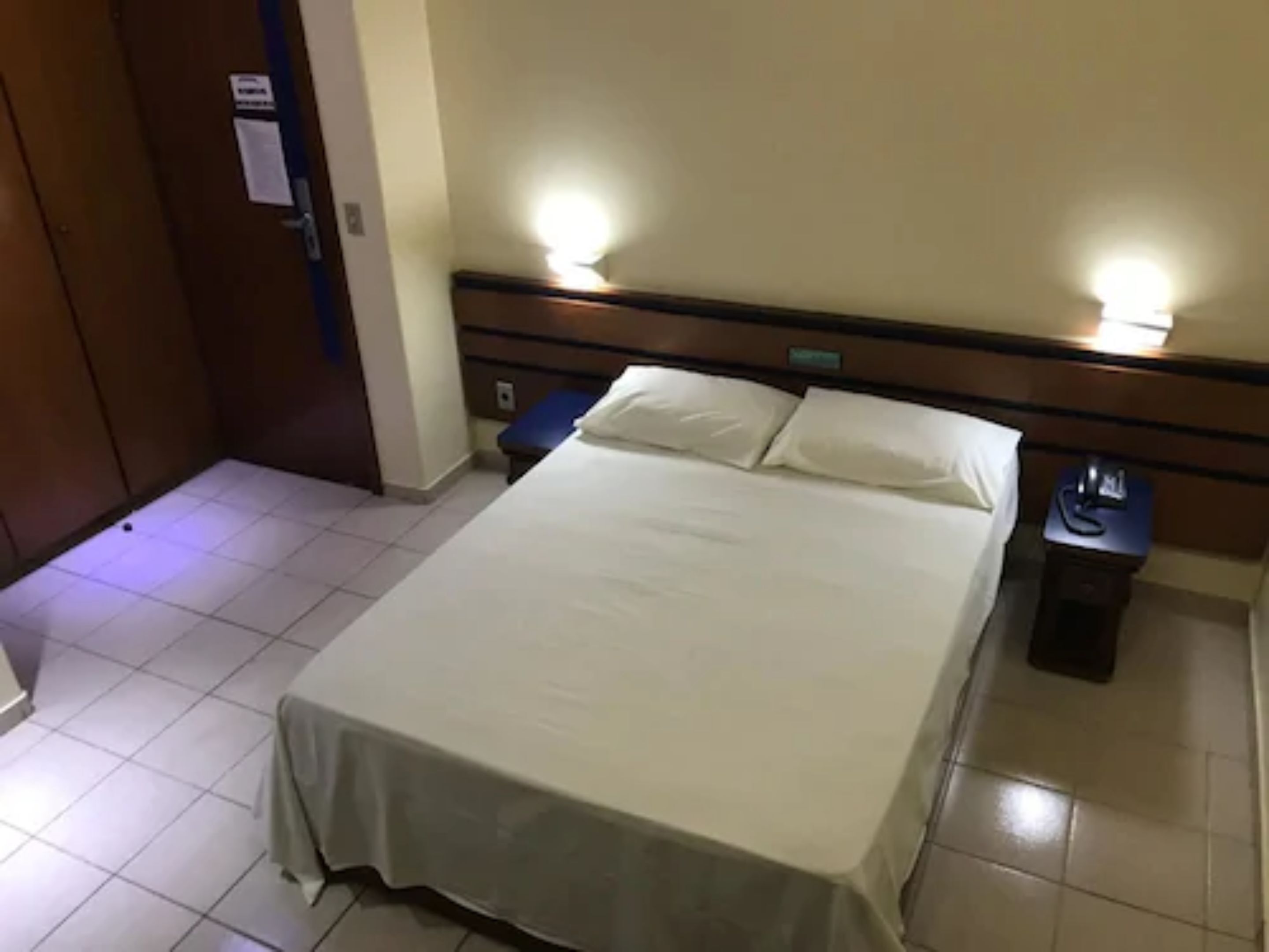 A hotel room with a bed, bedside tables, and a nightstand.