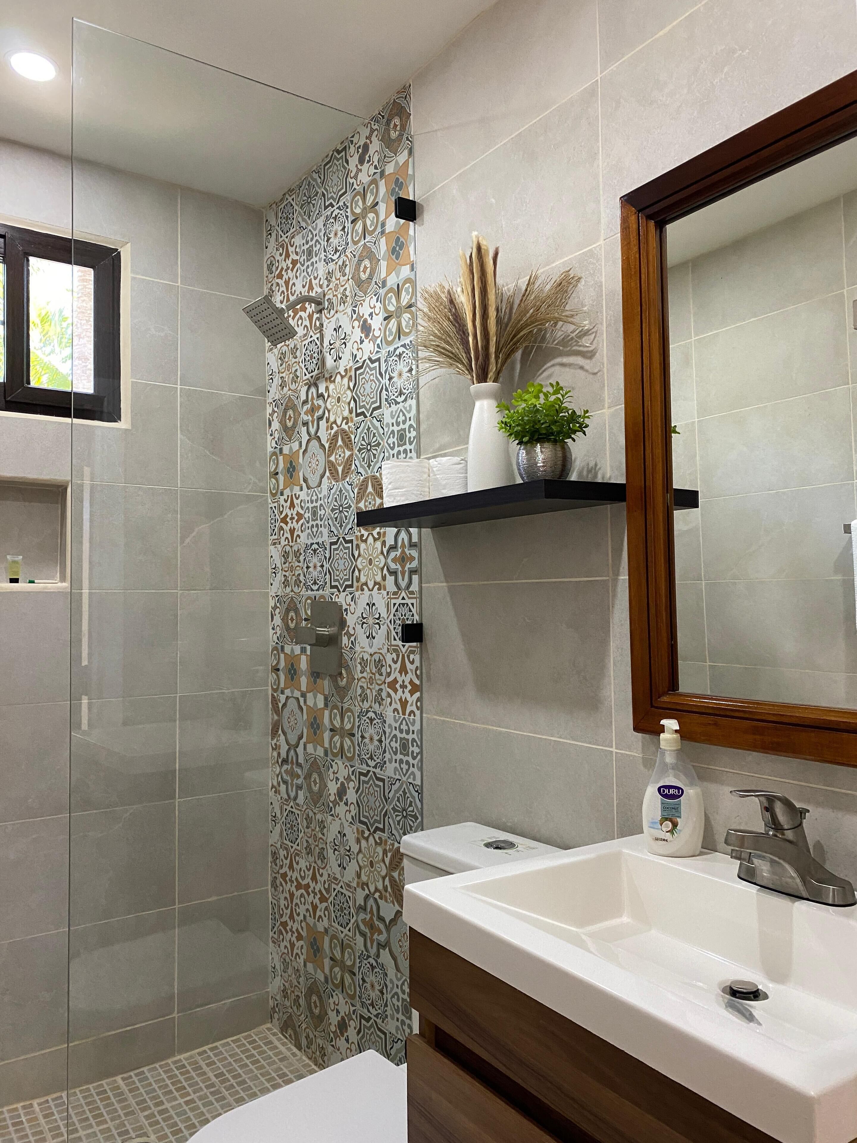 A modern bathroom with a shower, a sink, and a mirror.
