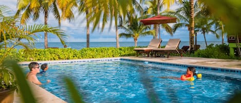 Una piscina al aire libre, sombrillas, sillones reclinables de piscina