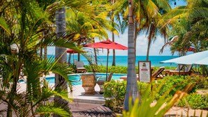 Un espace aménagé au bord de la piscine, avec des chaises longues, des parasols rouges et un panneau indiquant la zone où s’appliquent les « règles de la piscine ».