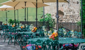 Eettafels buiten met stoelen, parasols en bloemdecoraties.