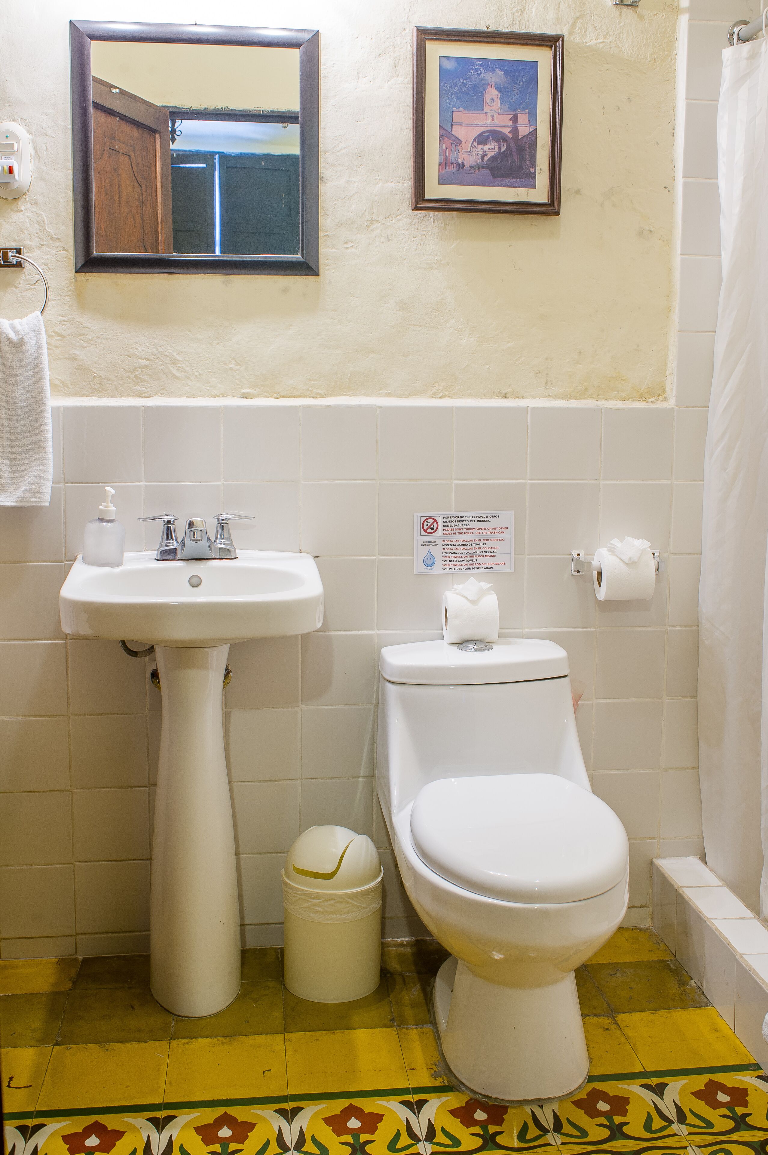 Un bagno con lavandino, water e un quadro appeso al muro.