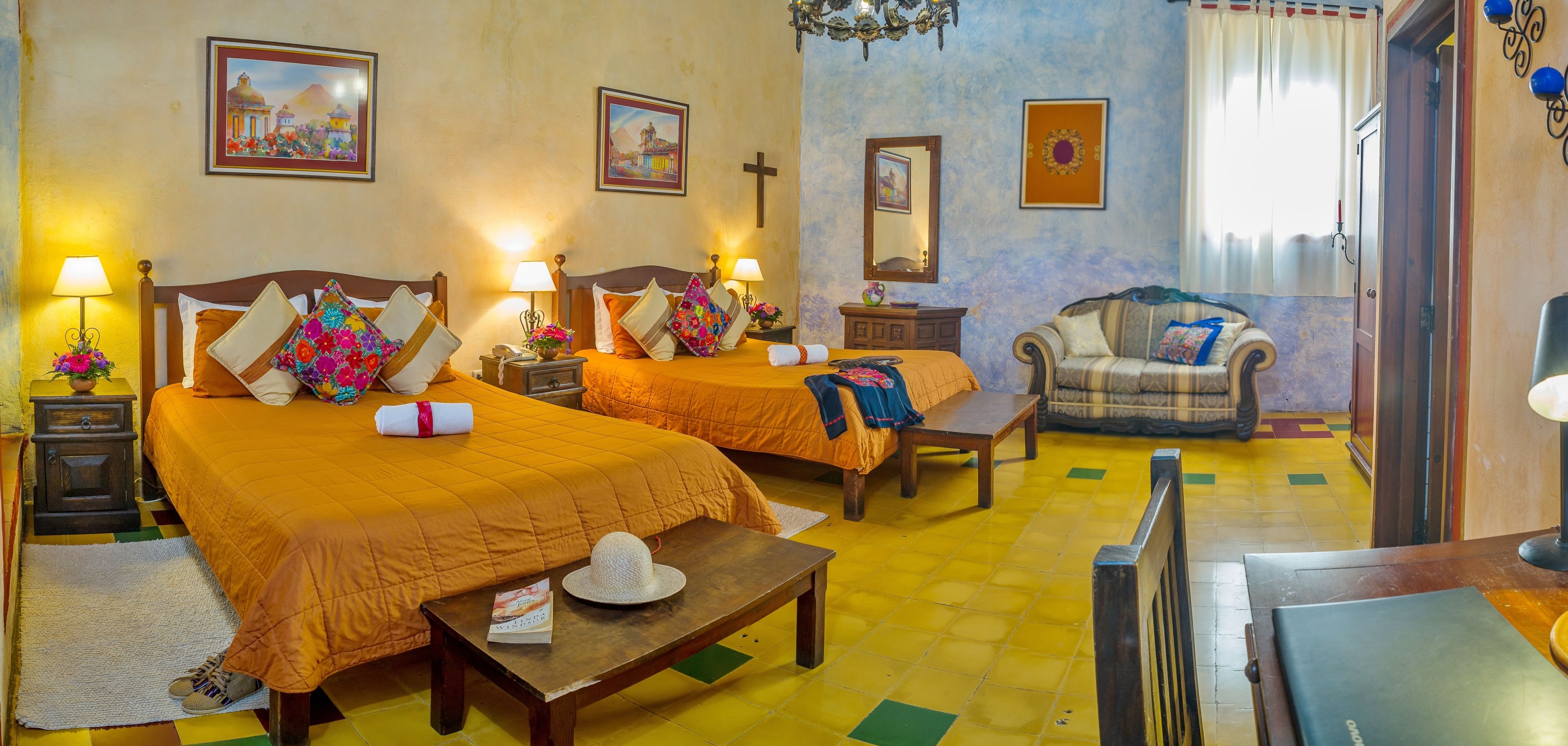 A hotel room with two beds, a sofa, a small table, and a TV.