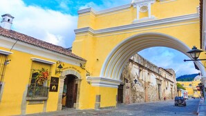 A yellow building with a clock tower and an archway. - Hotel Convento Santa Catalina (Antigua Guatemala)
