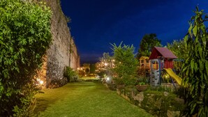 Ein Garten bei Nacht mit Spielplatz, Steinmauer und Rasenweg.