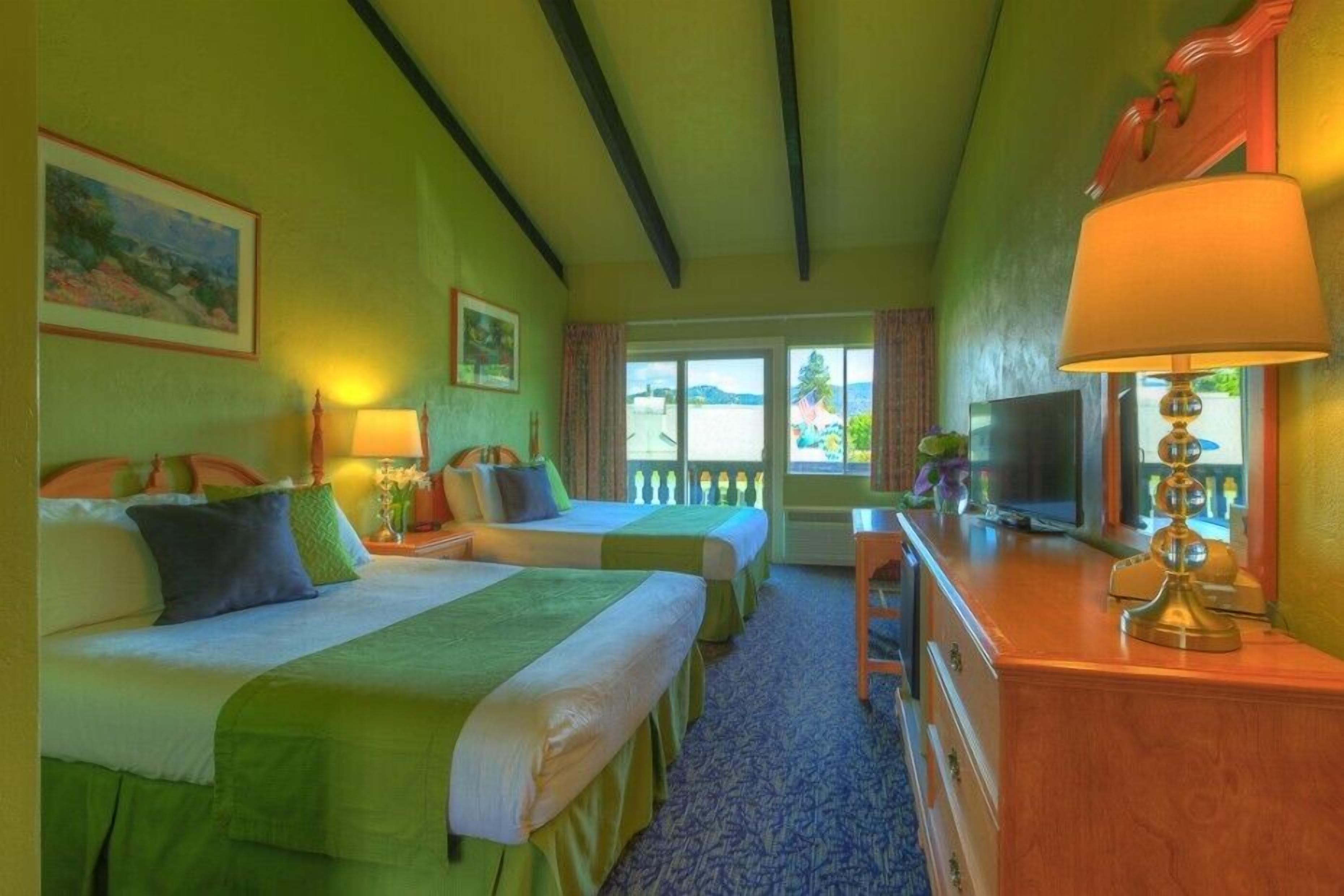 Habitación de hotel con dos camas, un escritorio, un televisor y vistas al exterior.