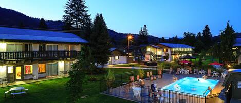 Un hotel con piscina, zona de estar al aire libre y vistas al bosque circundante.