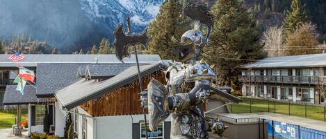A building with a mountain backdrop, a large decorative sculpture, and a flag.