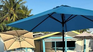 A pool area with a blue umbrella, lounge chairs, and a small table. - Sun Fun Resort (Nassau)