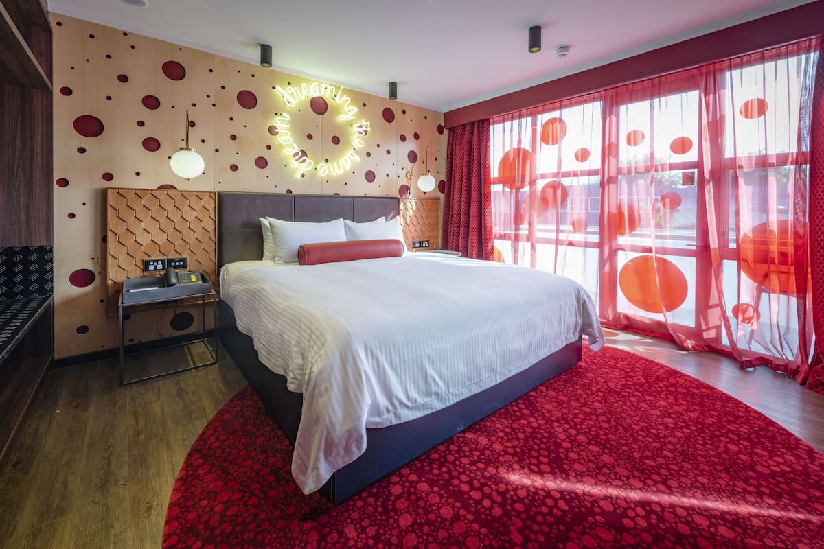 Een moderne hotelkamer met een groot bed, een houten accentmuur en een rood kamerkleed.