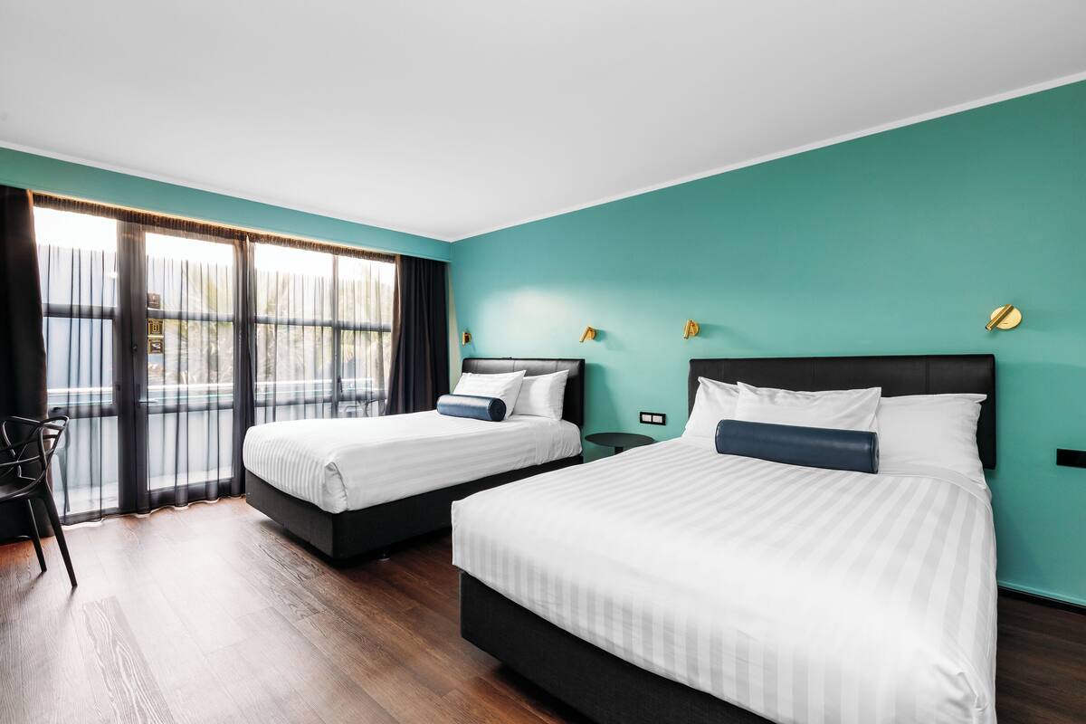 Een hotelkamer met twee bedden, een bureau en uitzicht op de omgeving.