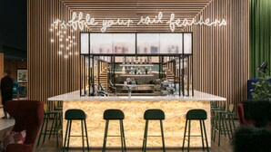 Un espace bar avec un décor en bois et un néon. On y trouve des tabourets de bar et un comptoir avec des bouteilles.
