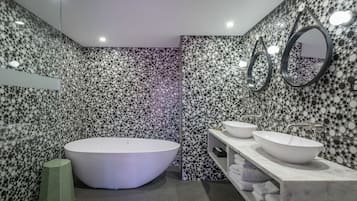A modern bathroom with a freestanding bathtub, two sinks, and a mirror.