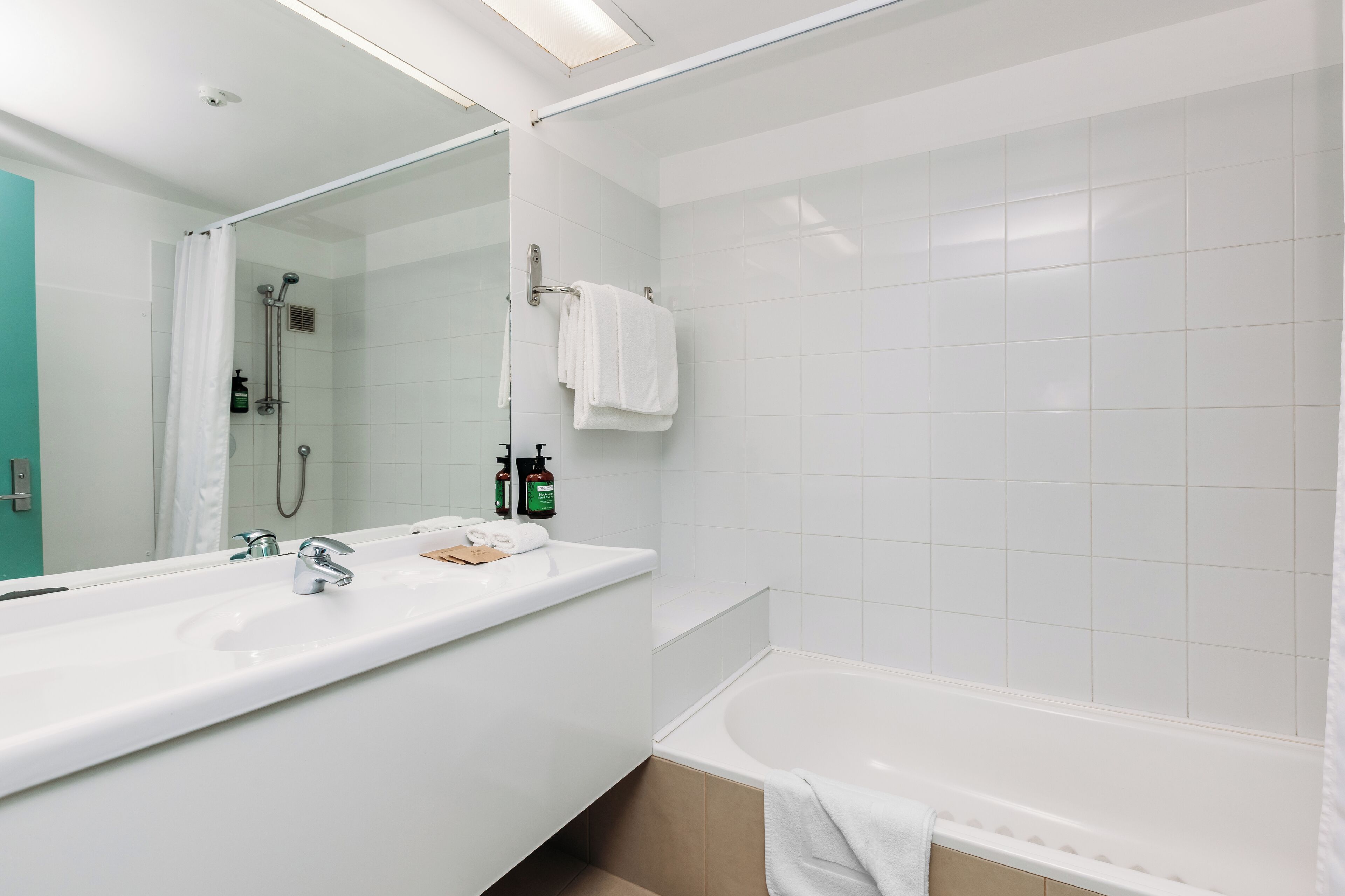 A modern bathroom with a large white sink, a bathtub, and a glass-enclosed shower.