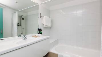 A modern bathroom with a large white sink, a bathtub, and a glass-enclosed shower.