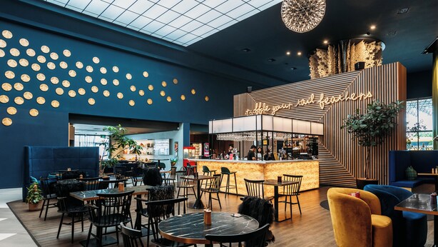 Un café moderne avec des tables rondes, un bar et un design de plafond original.