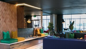 Un espace de détente moderne, doté de sièges, d’une grande fenêtre et d’une plante.