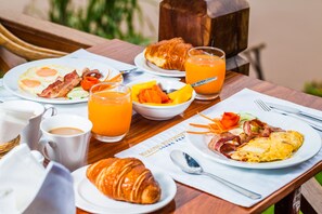 Een ontbijttafel met croissants, eieren, spek en sinaasappelsap.