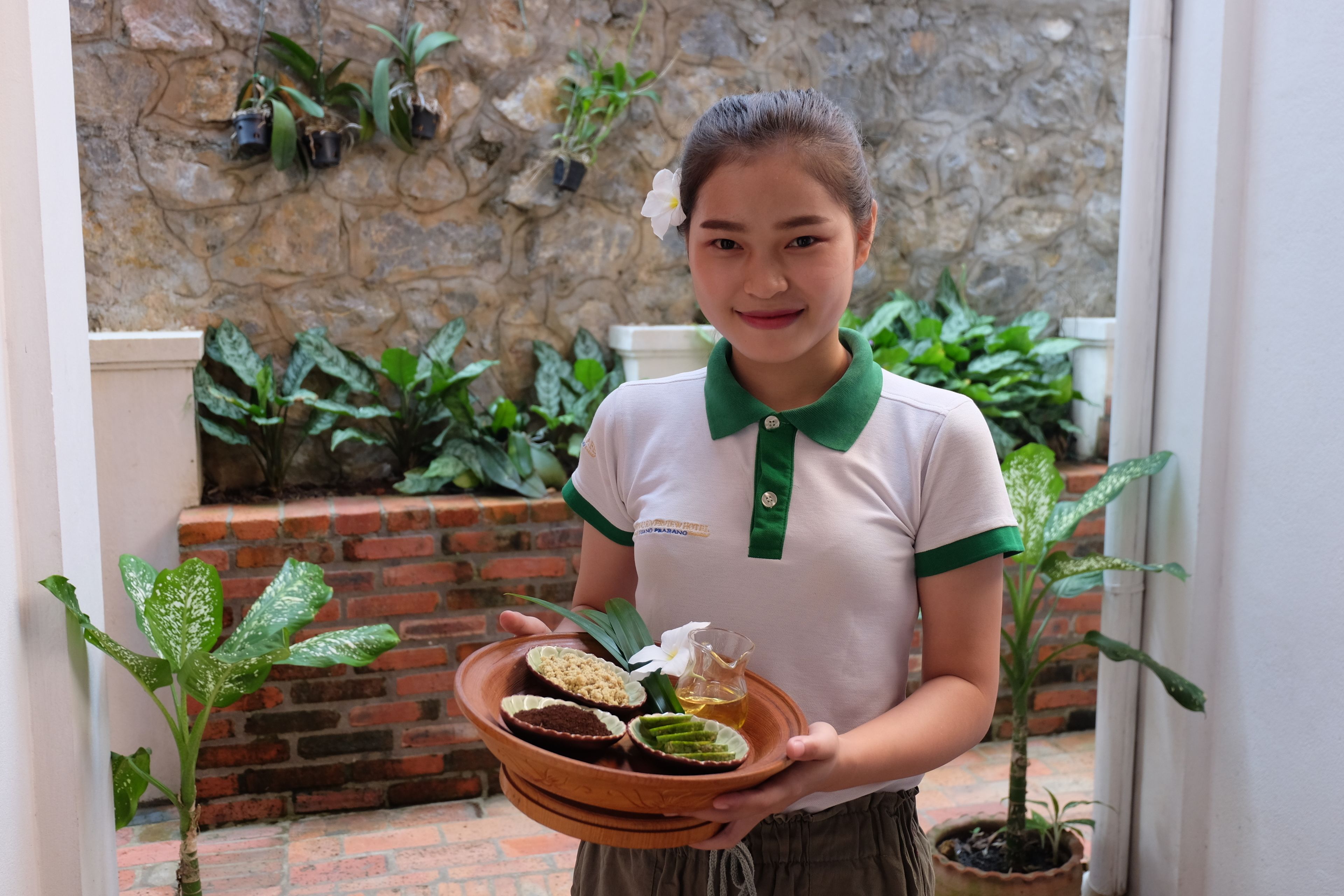 A person holding a tray with food items and a flower.