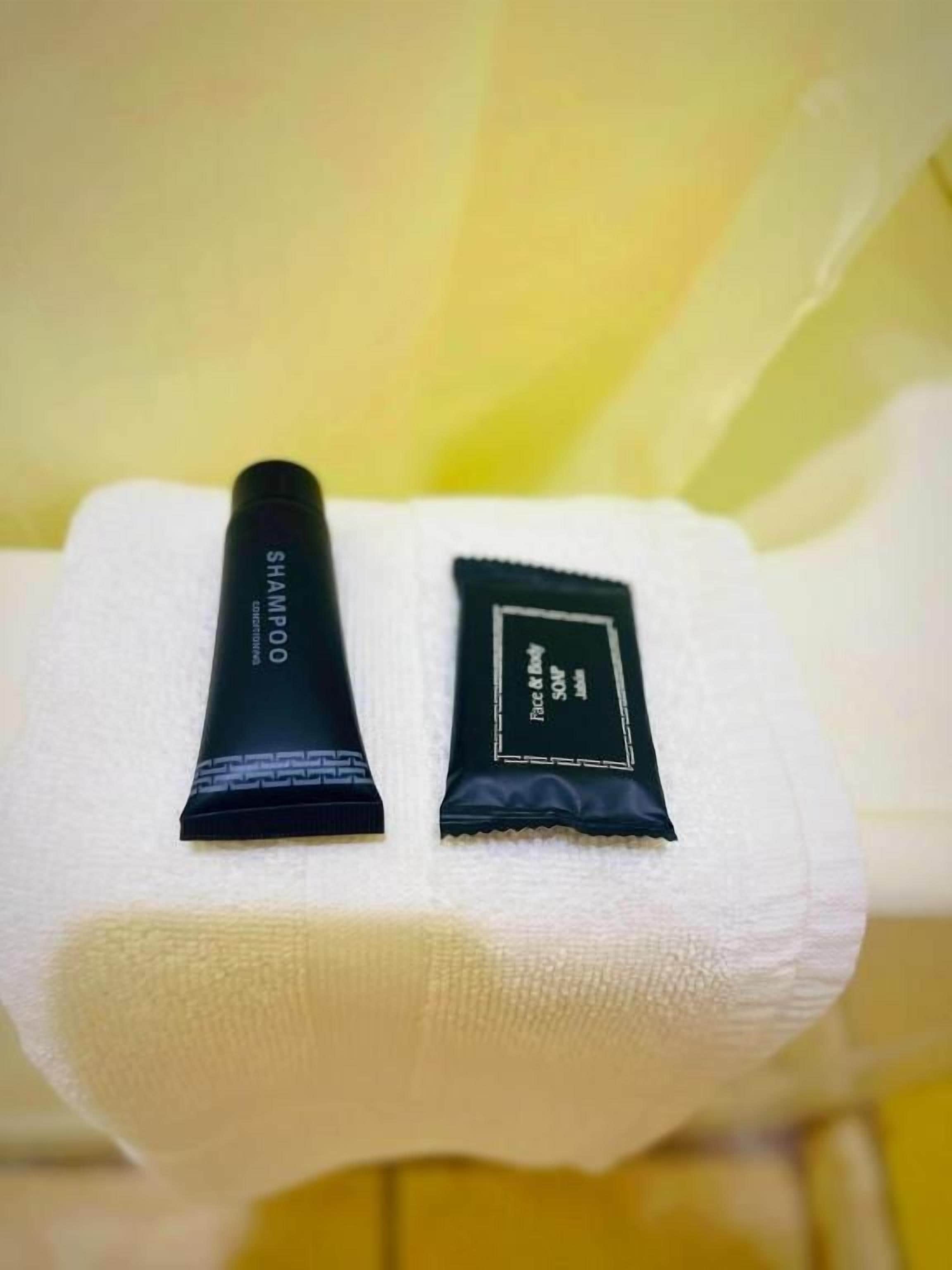 Two black tubes of shampoo and conditioner on a white towel.