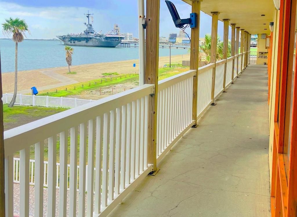 A covered walkway with a view of a large ship and a beach.