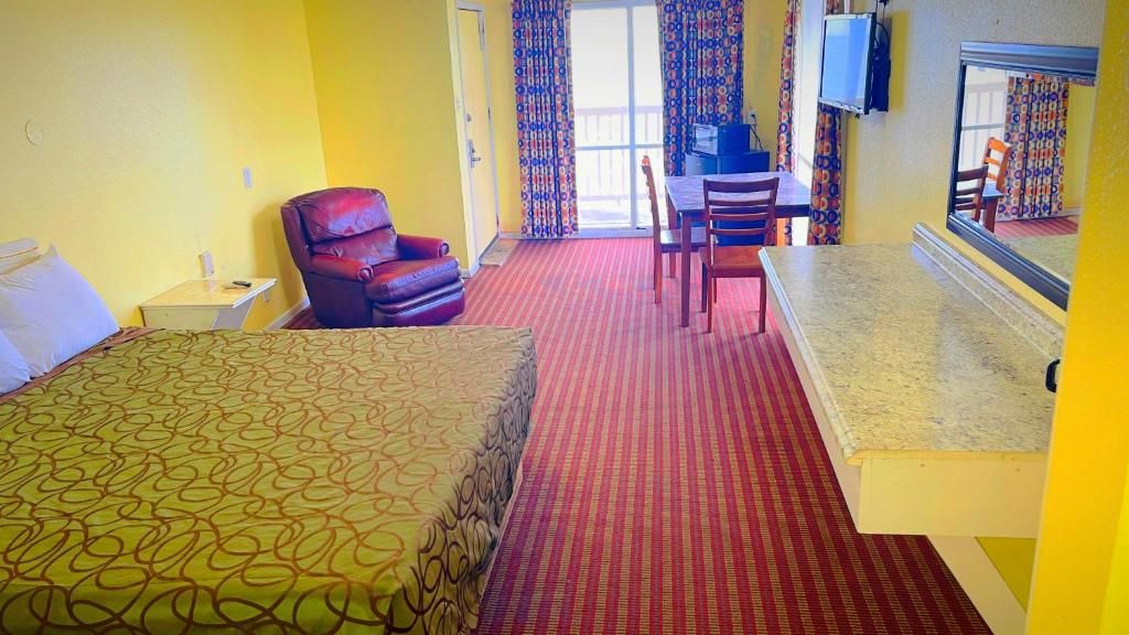 Una habitación de hotel con cama, una silla, escritorio y televisión.
