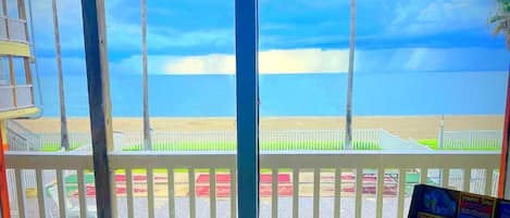 A pool area with a view of the beach and ocean, a lifeguard stand, and a signboard with text.