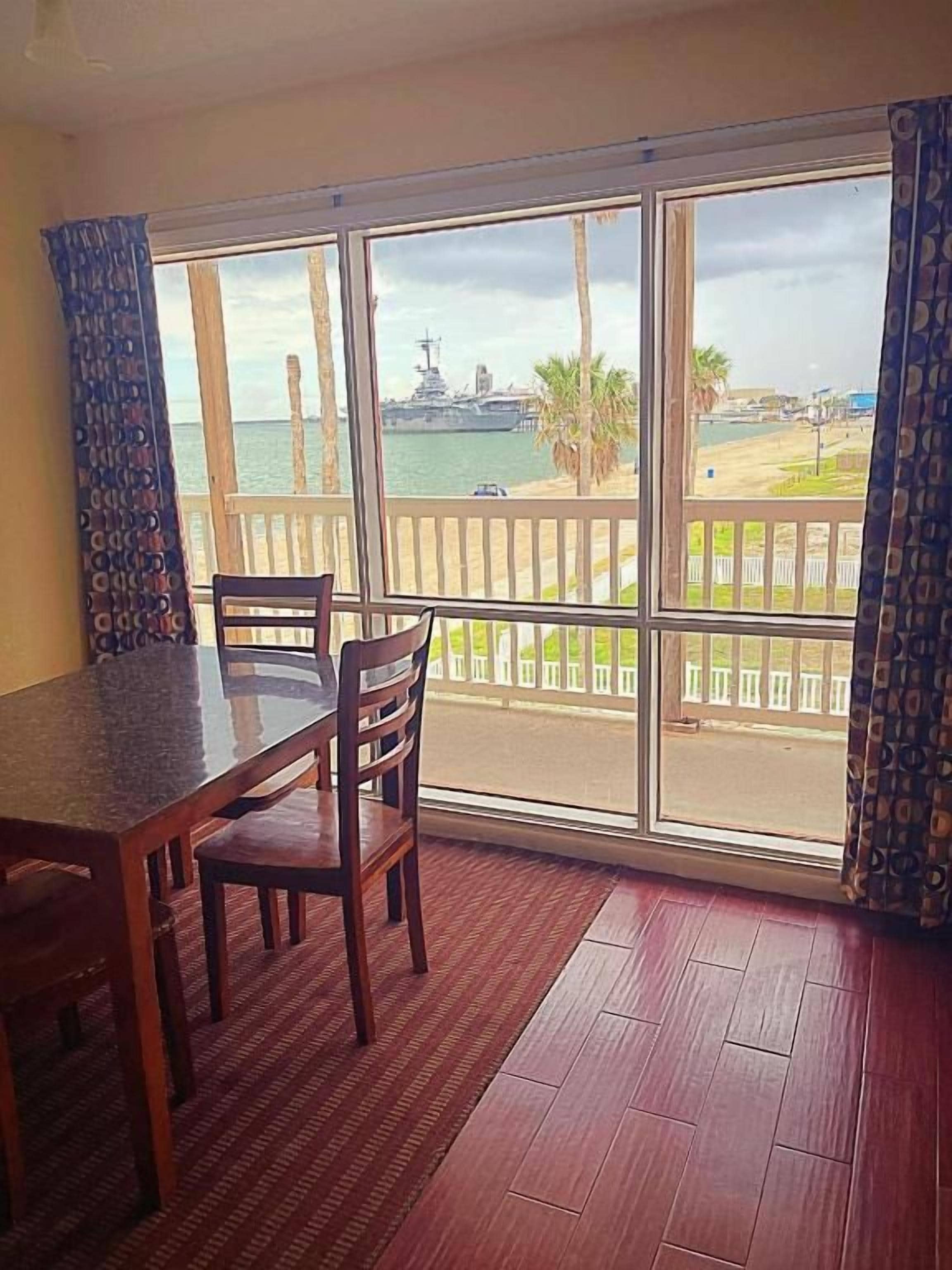 A room with a large window, a wooden table, and chairs.