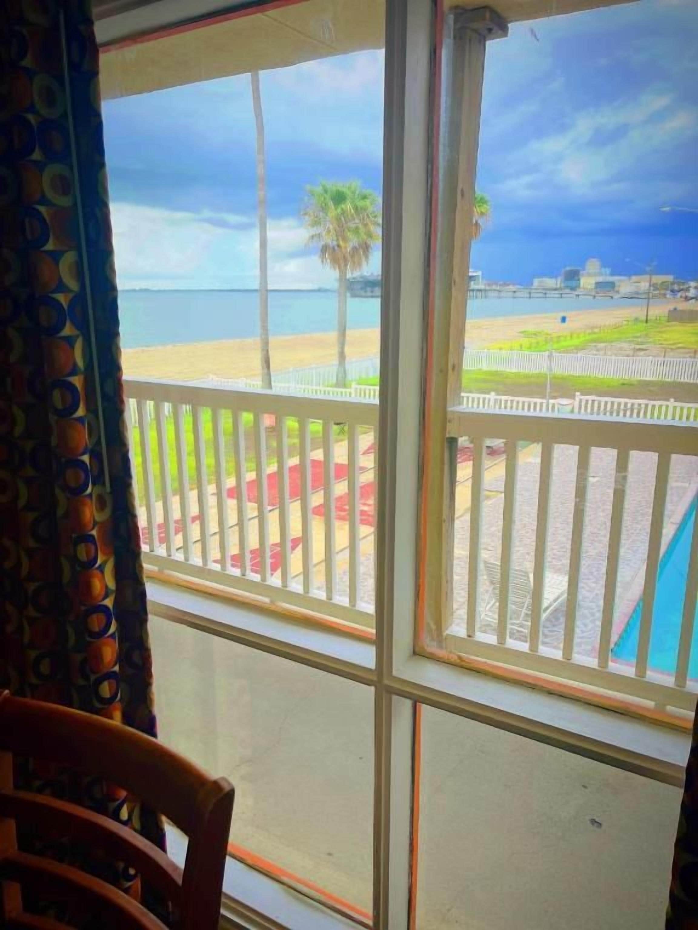 A room with a large window overlooking a beach and a cityscape.