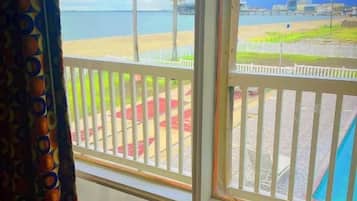 A room with a large window overlooking a beach and a cityscape.