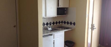A compact kitchen with white cabinets, a microwave, and a sink.