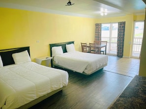A room with two beds, a small table, and a view of the outdoors. - Sea Shell Inn Motel (Corpus Christi)