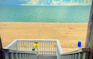 A beach view with a caution sign on a wooden railing. - Sea Shell Inn Motel (Corpus Christi)