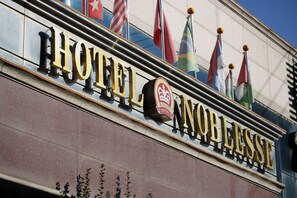 A hotel sign with flags and a logo. - Suncheon Noblesse Hotel (Suncheon)